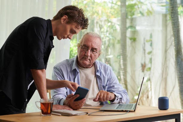 A son helps his father use his phone at home.